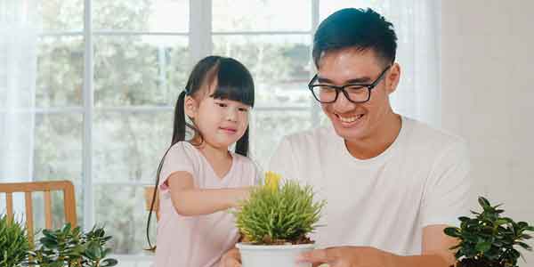 Asian man and daughter tending to house plants.